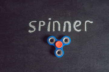 Famous fidget spinner stress relieving n a black wooden background. And the inscription spinner