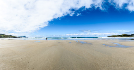 Mother and children are walking on sandy Atlantic beach.