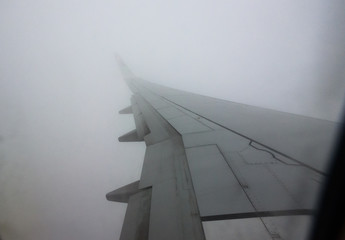 Looking trough window of an aircraft plane wing in fog.
