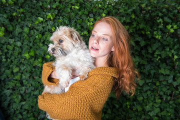 schöne rothaarige Frau hat ihren Hund auf dem Arm
