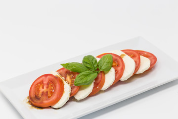 Slices of tomato and mozzarella salad on the white plate.
