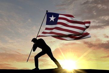 Liberia flag being pushed into the ground by a male silhouette. 3D Rendering