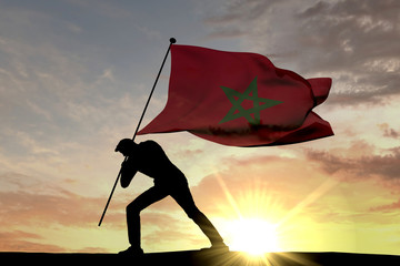 Morocco flag being pushed into the ground by a male silhouette. 3D Rendering