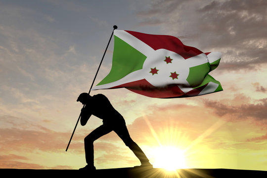 Burundi flag being pushed into the ground by a male silhouette. 3D Rendering