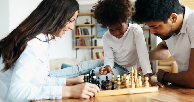 Happy family playing chess together at home