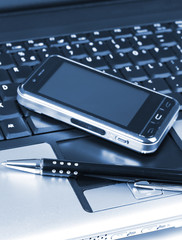 Mobile phone and pen on laptop