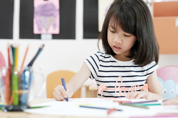 Girl drawing color pencils in kindergarten classroom, preschool and kid education concept
