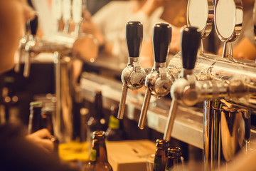 Beer tap with fresh brewed drink in busy pub in Europe - obrazy, fototapety, plakaty