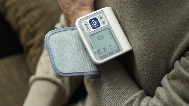 Measurement of blood pressure/An elderly man measures blood pressure by a tonometer mounted on the arm