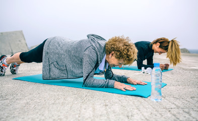 Senior woman with female coach doing plank exercise