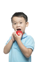 Asian baby boy holding and eating red apple, isolated on white