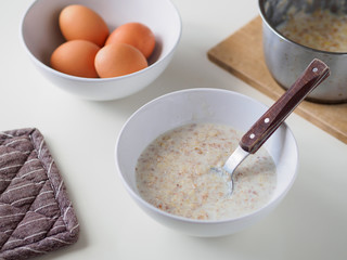 Breakfast with oatmeal and eggs. White table