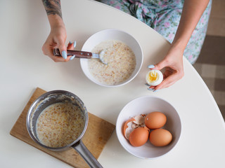 Breakfast with oatmeal and eggs. White table