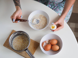 Breakfast with oatmeal and eggs. White table