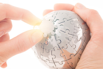 business concept with a hand building puzzle globe on white, space for messages