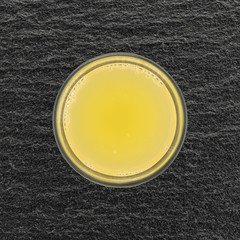 Top view of a glass of pineapple juice on a slate table.