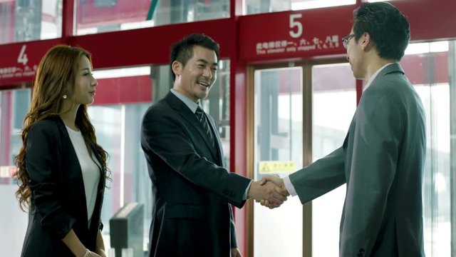 asian corporate executive greeting welcoming shaking hands with visiting client