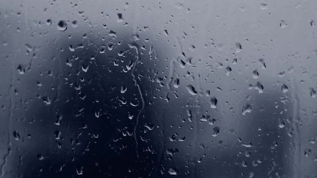 Dark blue rain drops on window glass.