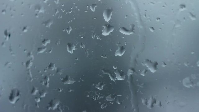 Sleet rain drops on window. Water drops running down a glass surface during a snowstorm.