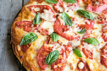 Hot Homemade Pepperoni Pizza on a rustic wooden table. Pizza with tomato, cheese and basil with copy space