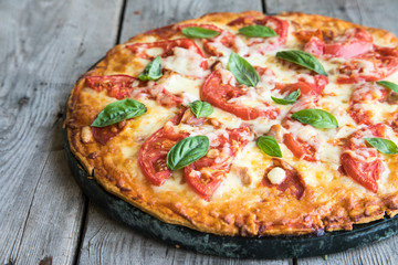 Hot Homemade Pepperoni Pizza on a rustic wooden table. Pizza with tomato, cheese and basil with copy space