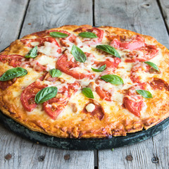Hot Homemade Pepperoni Pizza on a rustic wooden table. Pizza with tomato, cheese and basil with copy space