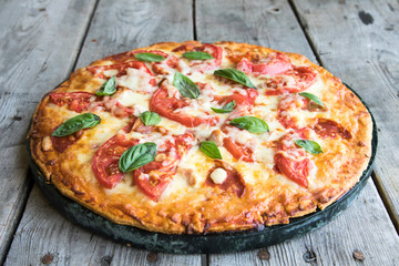 Hot Homemade Pepperoni Pizza on a rustic wooden table. Pizza with tomato, cheese and basil with copy space