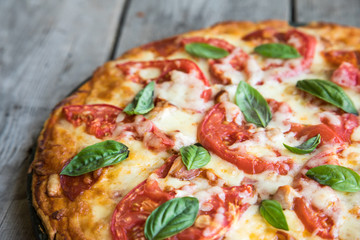 Hot Homemade Pepperoni Pizza on a rustic wooden table. Pizza with tomato, cheese and basil with copy space