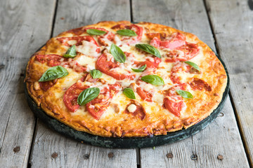 Hot Homemade Pepperoni Pizza on a rustic wooden table. Pizza with tomato, cheese and basil with copy space