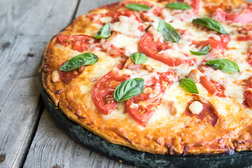 Hot Homemade Pepperoni Pizza on a rustic wooden table. Pizza with tomato, cheese and basil with copy space