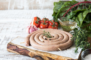 raw sausage for frying Grilled on vintage cutting board With thyme and tomatoes