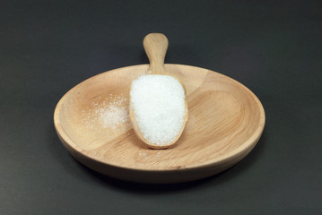 Sugar in a wooden spoon with a black background.