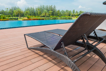 Sunbeds by the blue swimming pool and sky background .