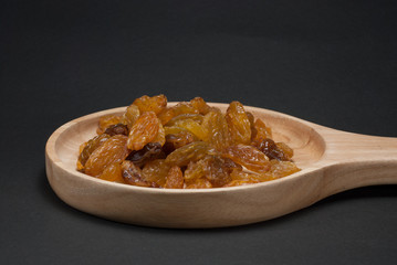 The raisin in the wooden dish has a black background.