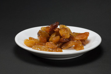 The raisin in the white dish has a black background.