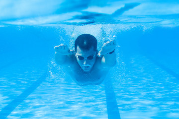 Underwater enjoyment. Young man swimming underwater and diving in the swimming pool. 