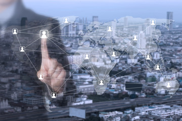 A Businessman using his finger  pressing social network icon with blurred background of big city.