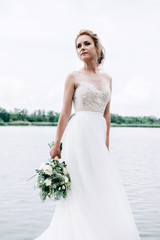 Fototapeta na wymiar Beautiful bride in the nature in a luxurious dress