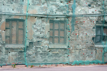 Brick wall of a building covered green construction facade mesh