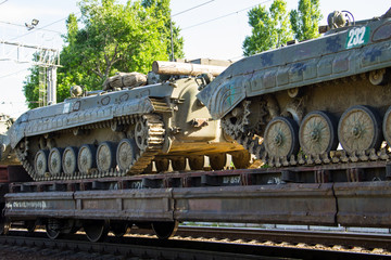 Cargo train carrying military tanks on railway flat wagons