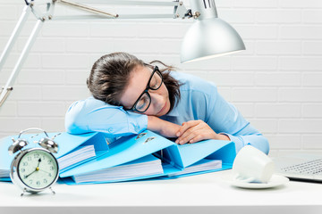 Businesswoman tired and fell asleep on reports in the office
