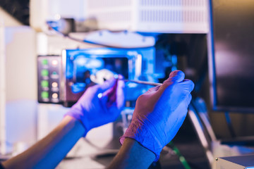 Scientist in a laboratory works with an electron microscope gateway. Putting a sample into a chamber