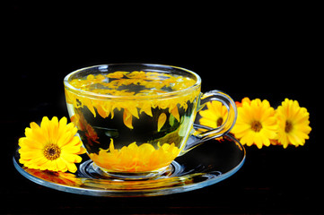 Calendula tea in transparent cup isolated on black background
