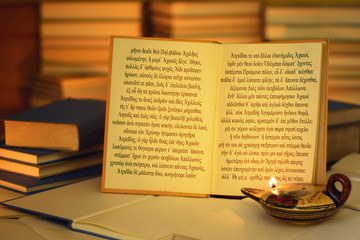 Open book illuminated by an oil lamp. The opening lines of The Iliad written in the ancient Greek...