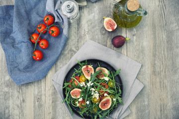 Fresh salad with arugula tomato and cheese on wooden background