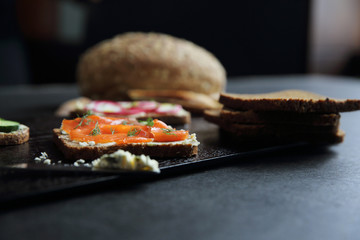 Sandwich with cereals bread smoked salmon beetroot and cucumber on dark marble background