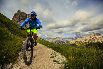 Obraz na płótnie Canvas View of cyclist riding mountain bike on single trail in Dolomites, Cinque Torri, South Tirol, Italy