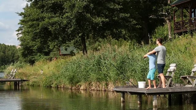 Father teaching son to fish at freshwater pond