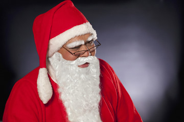 Close up of Santa Claus winking over colored background 