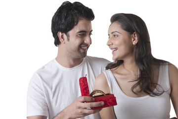 Loving young man gifting bangles to woman over white background